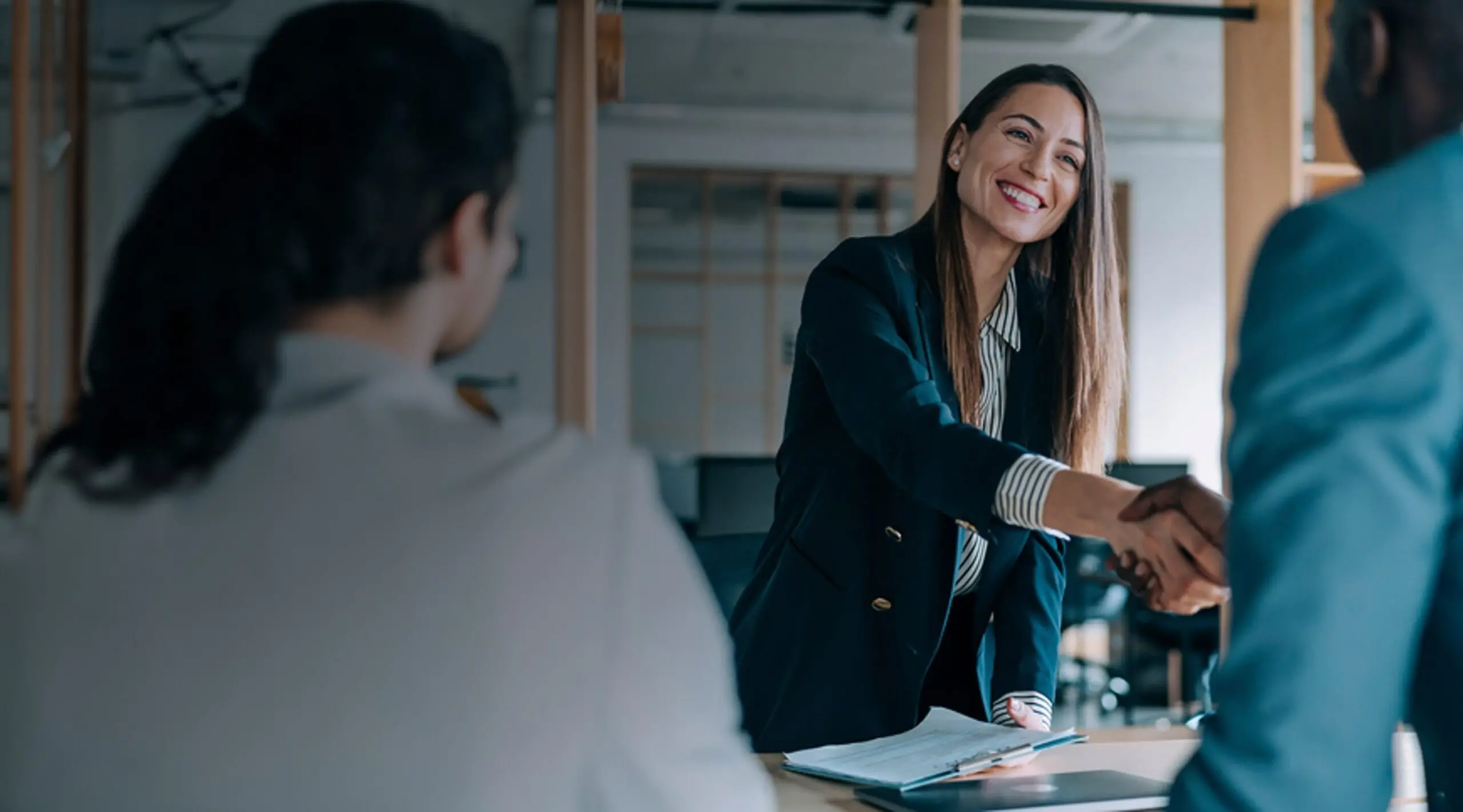 Leerink Partners Corporate Access - A smiling corporate woman reaching across the table, shaking hands with a corporate partner